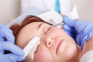 The plastic surgeon applies a bandage to the patient's eyelids after a blepharoplasty operation.