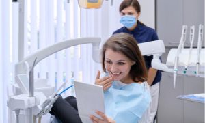 The woman looks at her teeth in the mirror after dental implant surgery.